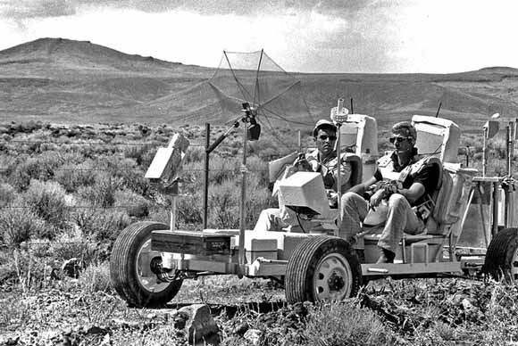 Astronauts driving lunar rover in desert